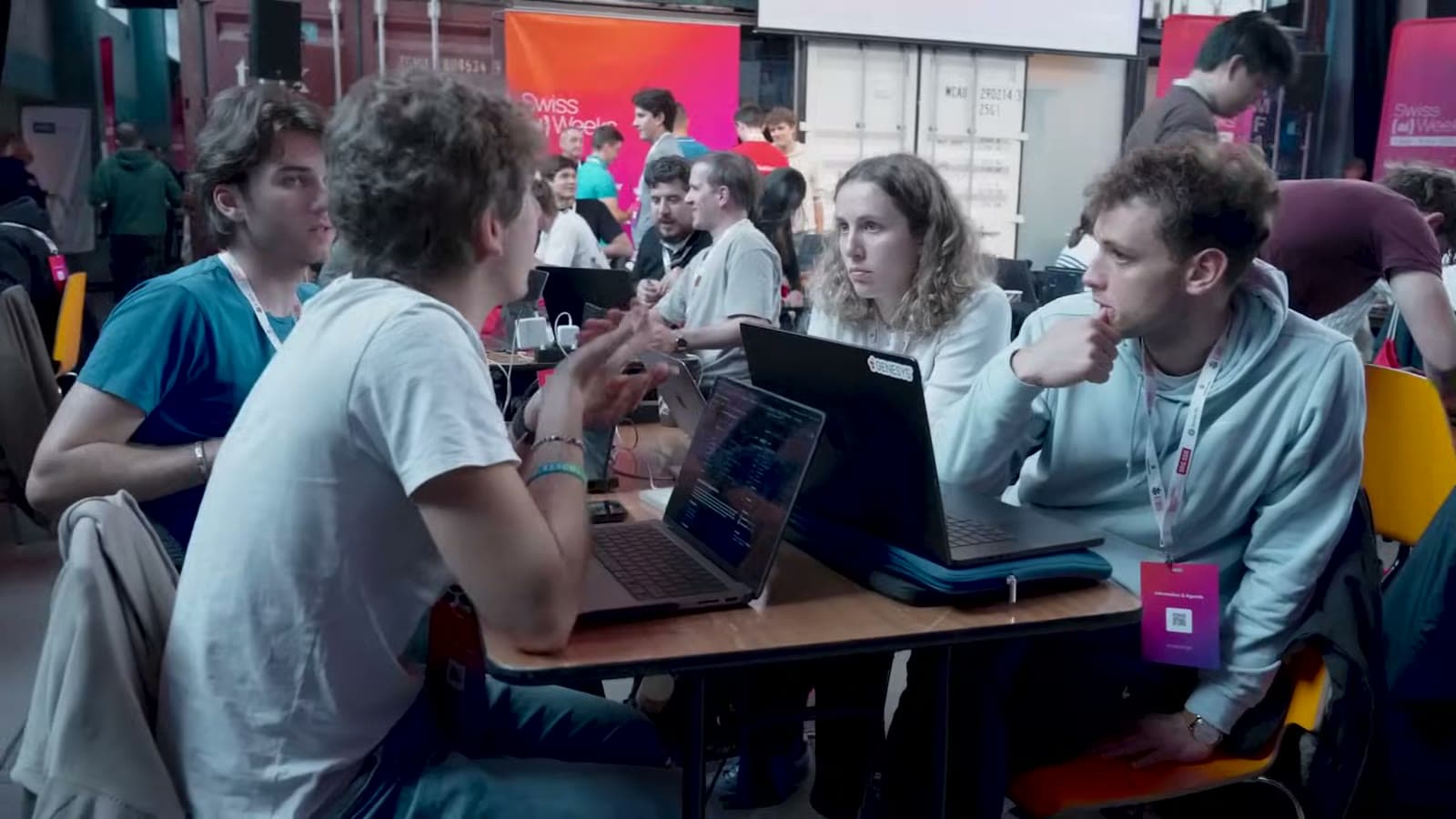 Hackers debating an idea around laptops at their team table