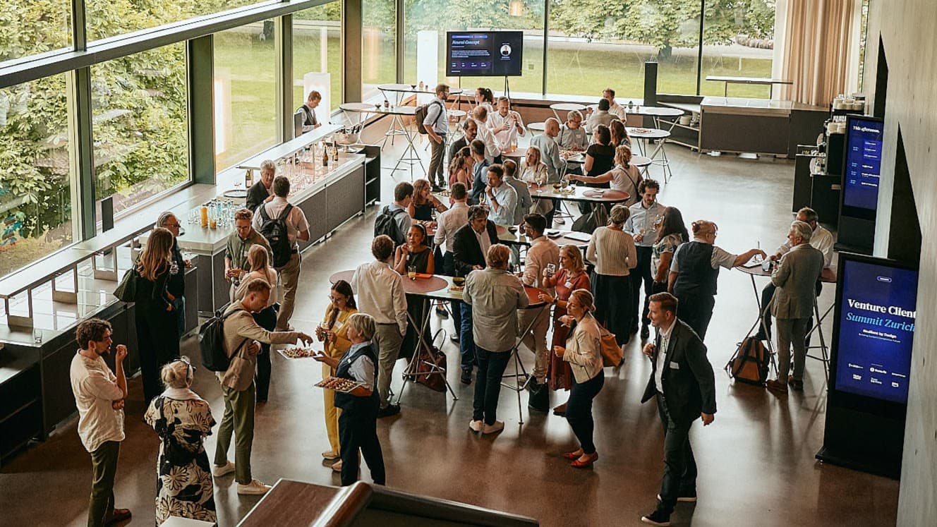 Guests networking around standing tables in a light-filled event foyer