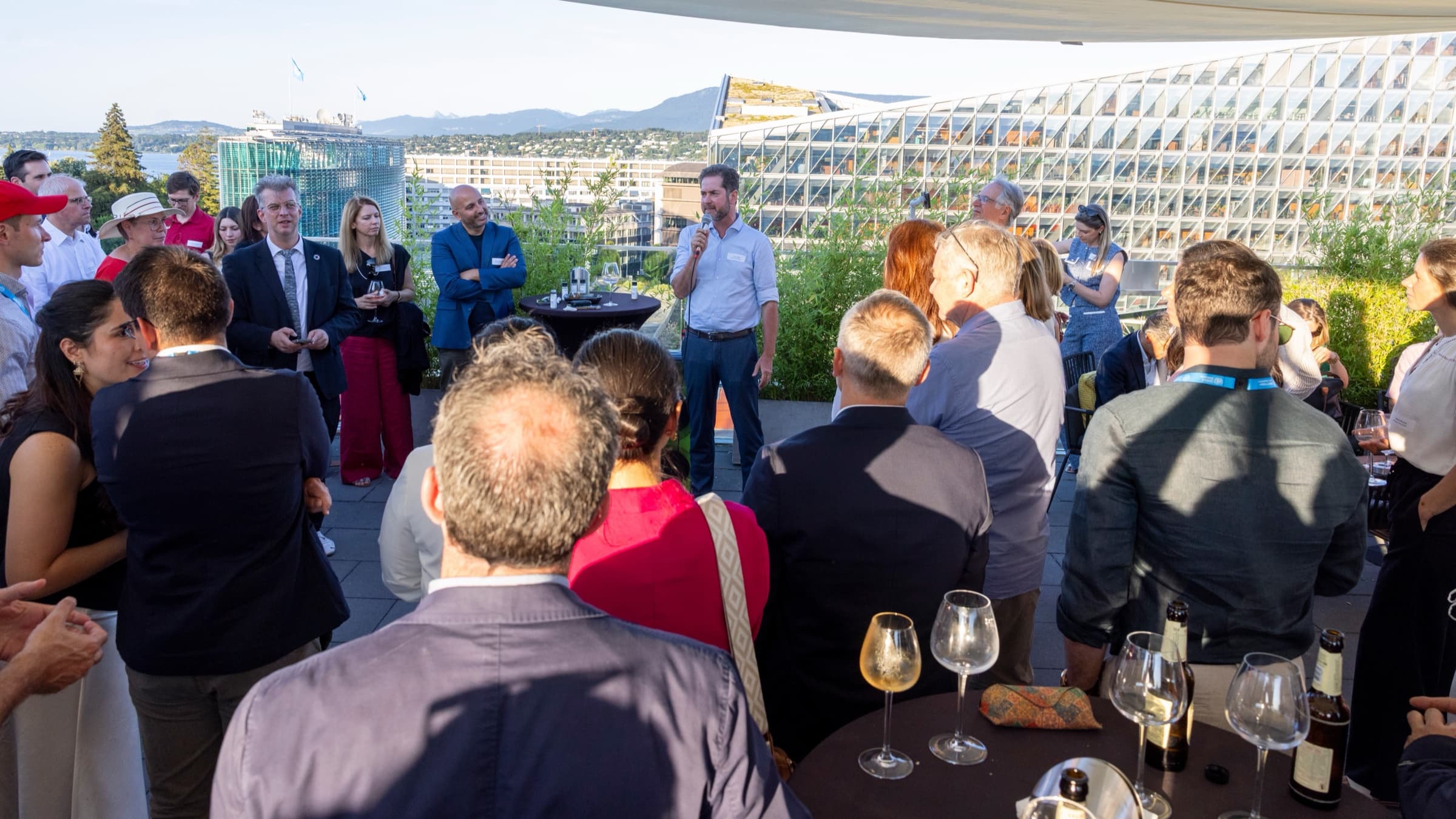 Speaker addressing guests at a rooftop reception above the city