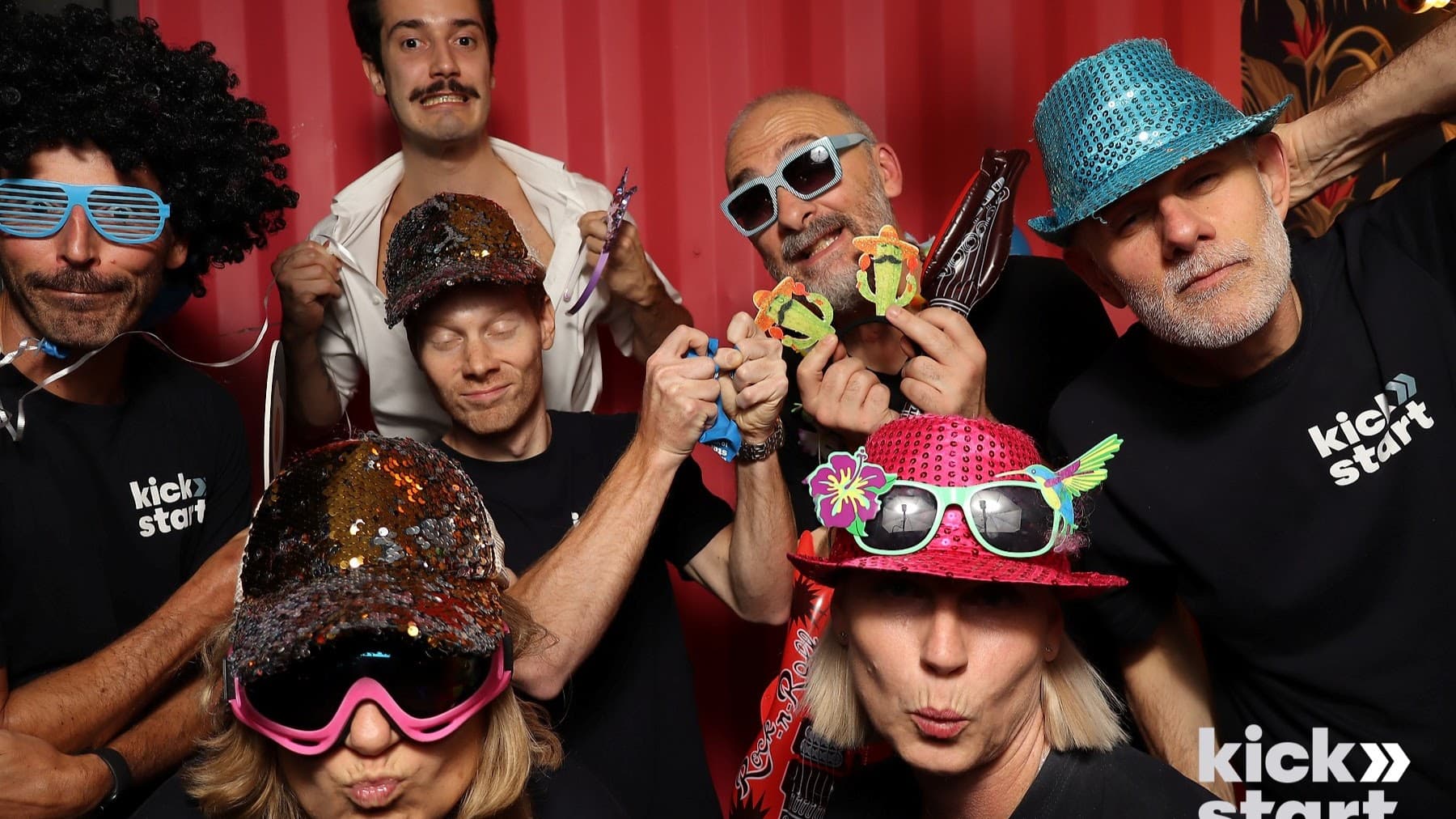 Volunteers posing with hats and props in a photo booth